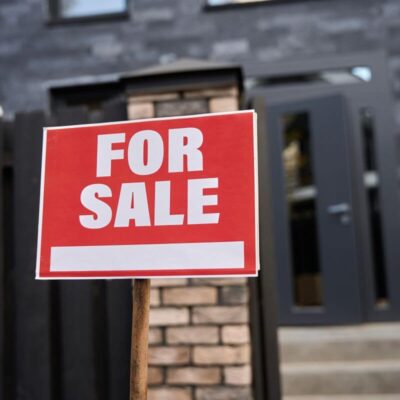 Znak "For Sale" przed wejściem sugeruje domy na sprzedaż.