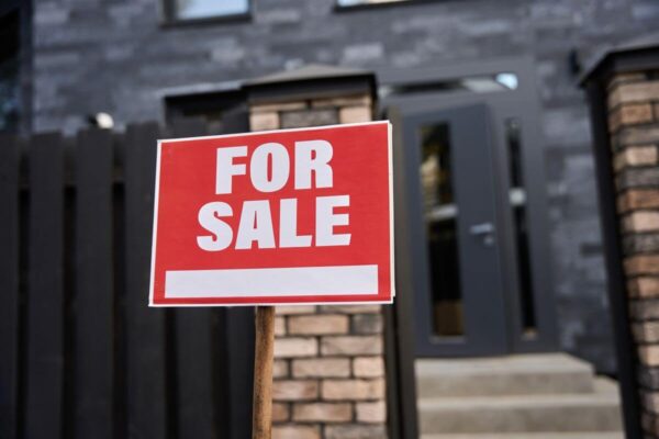 Znak "For Sale" przed wejściem sugeruje domy na sprzedaż.