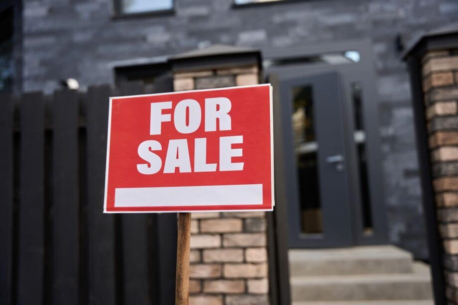 Znak "For Sale" przed wejściem sugeruje domy na sprzedaż.